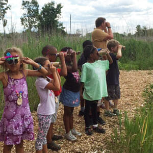 A group of children on Belle Isle on a path looking at birds through binoculars